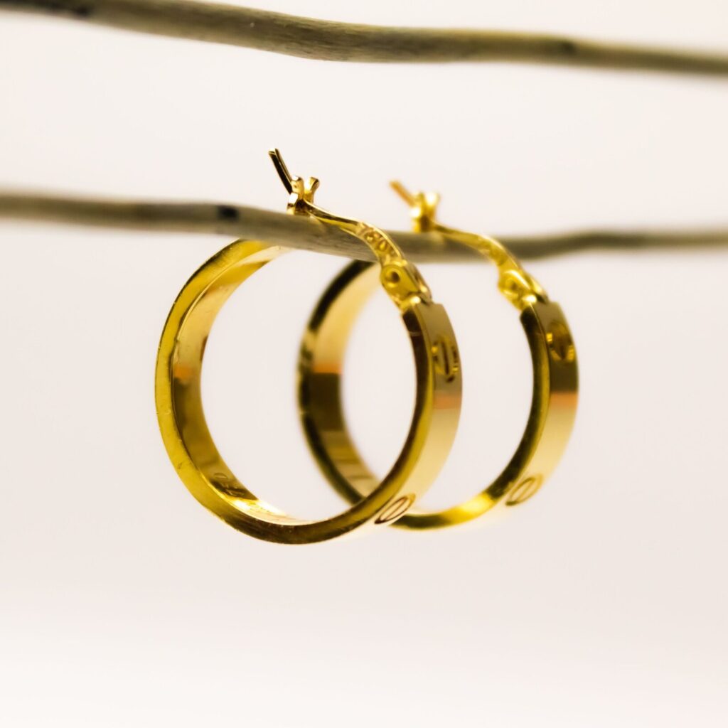 The golden hoop earrings hanging from a wire on the white background