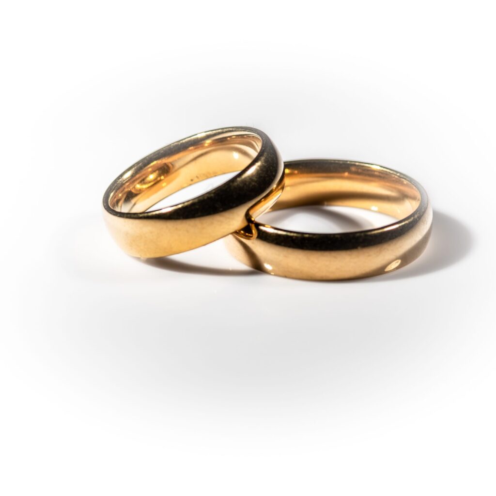 Two shining gold wedding rings isolated on white background, symbolizing the bond of marriage and everlasting love